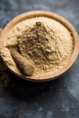 Ayurvedic Mulethi or Liquorice root stick or jeshthamadh powder served in a bowl over moody background