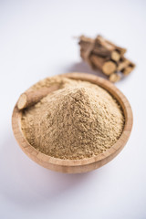 Ayurvedic Mulethi or Liquorice root stick or jeshthamadh powder served in a bowl over moody background