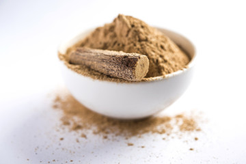 Ayurvedic Mulethi or Liquorice root stick or jeshthamadh powder served in a bowl over moody background