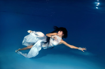 Bride in white dress underwater in the pool. Underwater wedding