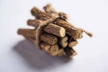 Ayurvedic Mulethi or Liquorice root stick or jeshthamadh powder served in a bowl over moody background