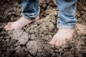 Human stand barefoot in soil. His feet is stained and dirty.