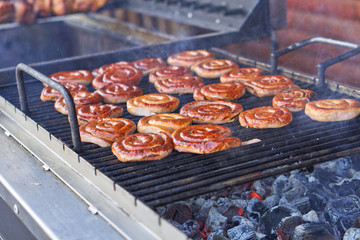 Grilled sausage on a grill with a delicious crust on the background of vegetables. Summer holidays and food in nature. Stock Photo