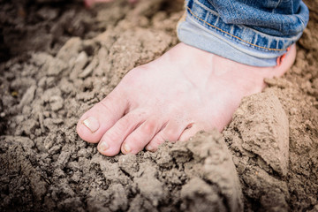 Human stand barefoot in soil. His feet is stained and dirty.