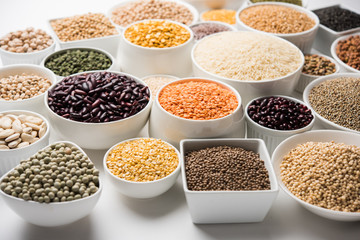 Uncooked pulses,grains and seeds in White bowls over white background. selective focus