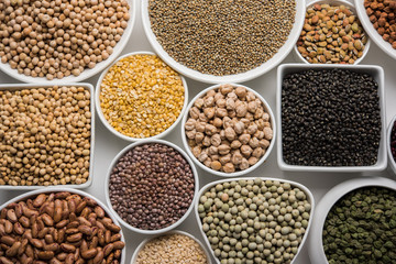 Uncooked pulses,grains and seeds in White bowls over white background. selective focus