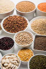 Uncooked pulses,grains and seeds in White bowls over white background. selective focus