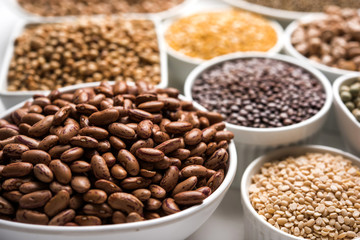 Uncooked pulses,grains and seeds in White bowls over white background. selective focus