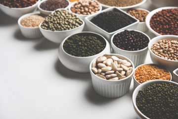 Uncooked pulses,grains and seeds in White bowls over white background. selective focus