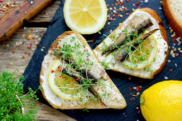 Smoked sprat lemon microgreens sandwiches on black slate plate