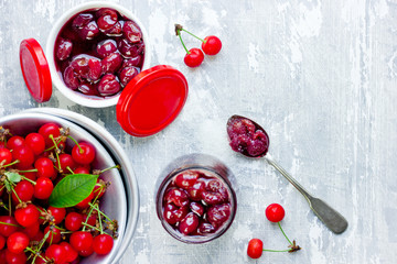 Delicious cherry jam in sugar syrup and fresh cherries in bowl on whitewash gray background