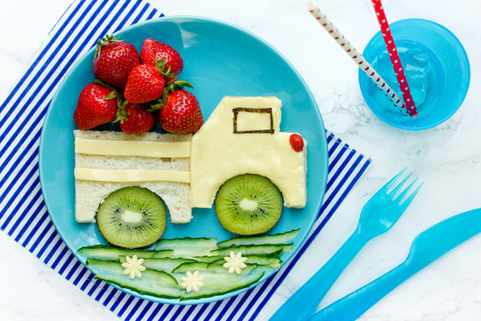 Funny food idea for kids - cheese sandwich with strawberry and kiwi shaped car on a plate top view