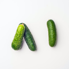 Green vegetables flat lay concept. Cucumber on white background, top view with empty space for text.