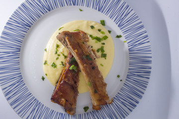 White Round plate with baked pork ribs and corn meal mush isolated on white background