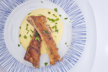 White Round plate with baked pork ribs and corn meal mush isolated on white background