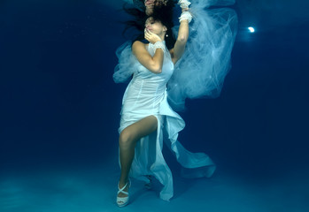 Fototapeta na wymiar Bride in white dress underwater in the pool. Underwater wedding