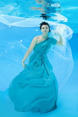 Fototapeta na wymiar beautiful woman in a long dress posing under water (for the calendar, winter, February)