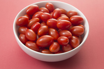 Grape Tomatoes in a White Bowl on a Red Background