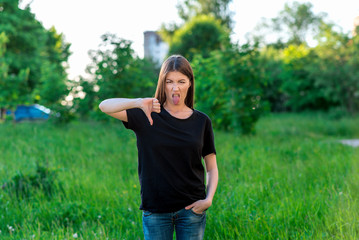 Beautiful national girl. In the summer in the park in nature. With a gesture of the hand and shows a finger down. Shows the language. Dissatisfied disapproval. Narrowing his eyes. Negative Emotional