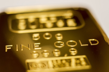 The surface of gold bullion. The texture of the surface of the minted gold bar. Selective focus, shallow DOF.