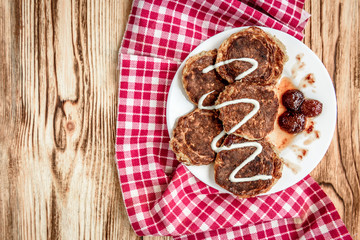 Homemade oat pancakes with strawberry jam and sour cream on wooden background. Healthy breakfast.
