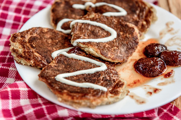 Homemade oat pancakes with strawberry jam and sour cream on wooden background. Healthy breakfast.