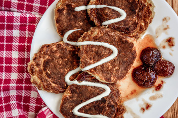 Homemade oat pancakes with strawberry jam and sour cream on wooden background. Healthy breakfast.