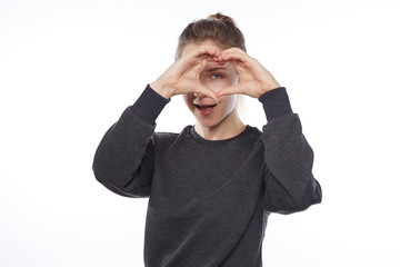 Naklejka premium Young European female with pretty look, blond hair, dressed sporty, shows love sign with hands cupped in heart shape, feels love to someone, stands isolated over white studio wall background.