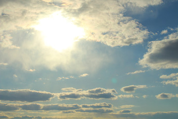 Blue sky and gray clouds. The sun shines through thunderclouds. Background. Landscape.