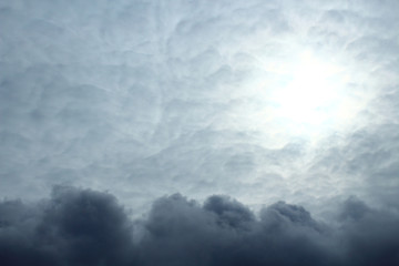 Dark cumulus clouds and pale sun. Overcast. Storm clouds. Background. Landscape. Texture. Spring,...
