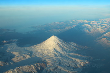 Demavend. Sleeping stratovolcano in the mountain range of Elbors (Alborz), in the north of Iran, in the southern part of the Mazandaran. View from the airplane window. March, 2018.