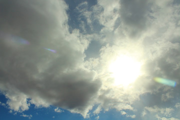 Blue sky and gray clouds. The sun shines through thunderclouds. Background. Landscape.
