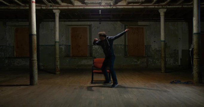 A stunt performer practices a fight scene in which he gets free from his ties and fights off attackers in an abandoned building