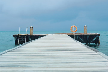 Naklejka premium Perspective view of a wooden pier on the tropical seashore sea with turquoise water.