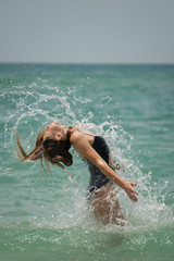 Beautiful young girl splashing in the sea