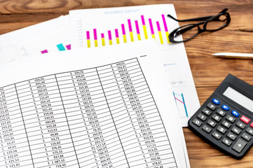 Naklejka na ściany i meble Document with financial data over table with paper business graphs and calculator.