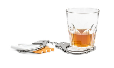 Glass of alcohol drink and cigarettes with handcuffs on white. Bad habits concept.