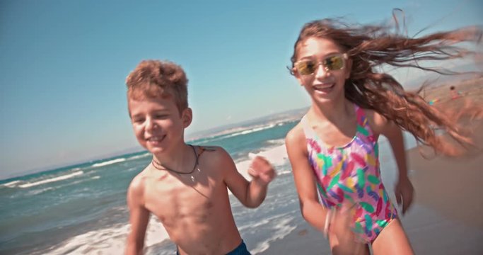 Young boy and girl having fun running on island beach