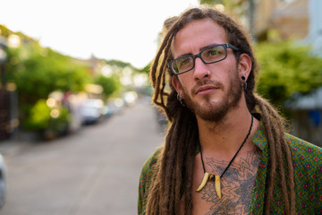 Young handsome Hispanic tourist man with dreadlocks in the stree