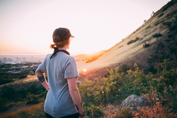 Fototapeta premium Girl hiking and looking at sunset