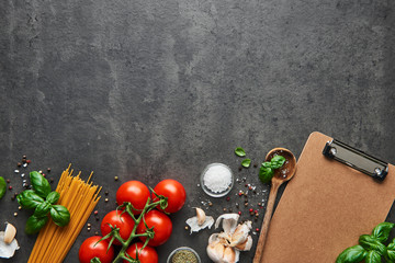Fototapeta na wymiar Food background for tasty Italian dishes with tomato. Various cooking ingredients with spoon and blank cardboard clipboard for menu or recipes. Top view with copy space.