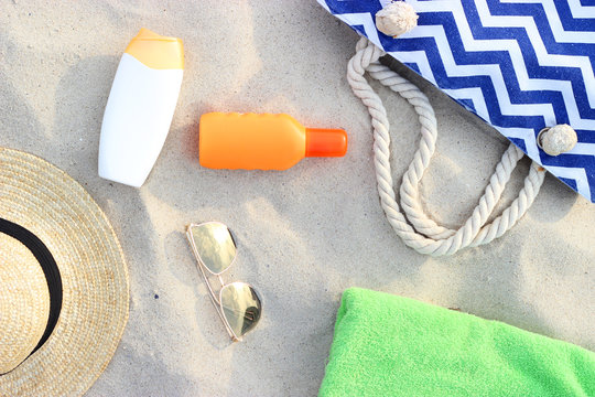 sunscreen, towel, glasses on a sand background view from above. flatlay