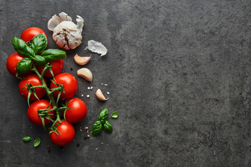 Food background. Flat lay of fresh tomatoes with basil, garlic and seasalt on black stone background. Top view with copy space on the right. - Powered by Adobe