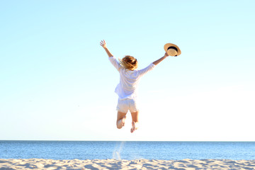the girl is jumping against the sea.