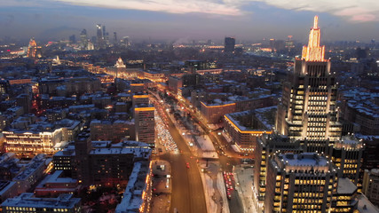 Aerial shooting of Moscow Garden Ring in the evening. City lights in the dusk. Business center "Armory" tower at sunset.