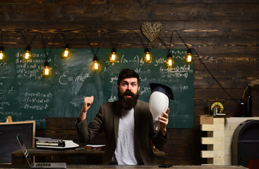 Genius man with beard hold bulb on chalkboard. Genius businessman with lightbulb got idea in classroom, enlightenment