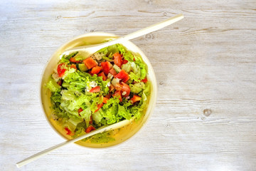 bowl of salad with vegetables and greens on wooden table