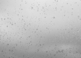 Rain drops, water drops of rain on a window glass blue background, abstract defocused with space