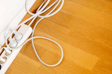 Multiple socket and plugs on wooden floor.
