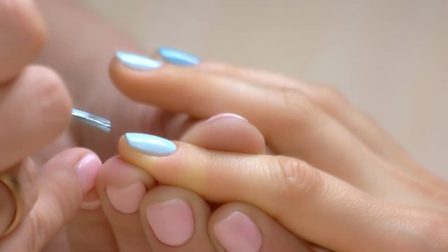 Nail salon manicure workshop. Female manicure master applies blue color polish gel on healthy woman nails. Skin and nails care concept.